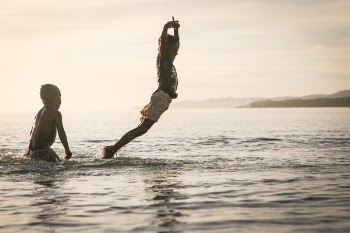Boy Floating over Water Near Boy Standing on Side
