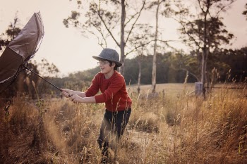 Boy Holding Black and Brown Umbrella in the Middle of Forest