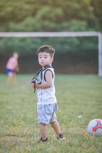 Boy Holding Camera Looking to His Back