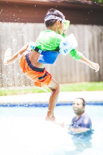 Boy in Green Crew-neck Shirt and Orange Shorts Jump over Swimming Pool