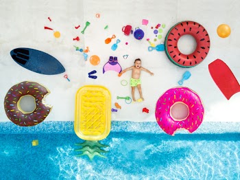 Boy in swimming pool surrounded with toys