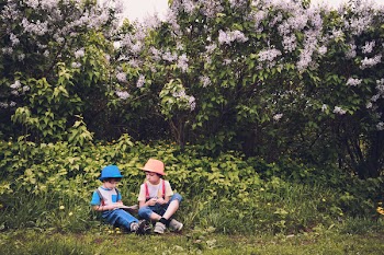 Boy in White and Blue Shirt and Blue Jeans Sitting in Green Grass