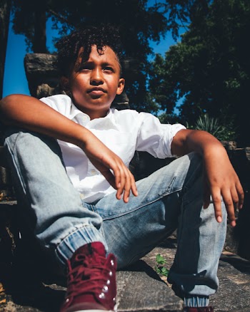 Boy in White Shirt and Faded Blue Jeans Sitting on Ground