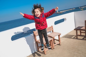 Boy Jumping Near Brown Wooden Chairs