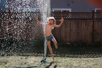 Boy Jumping Near Sprinkler