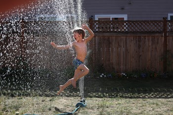 Boy Jumping on Water Sprinkler