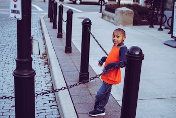 Boy Leaning On Chain Fence