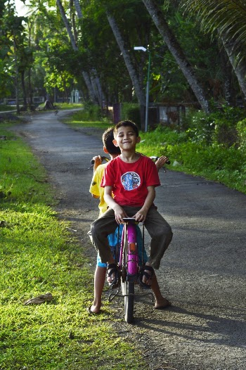 Boy Riding on Back of Bicycle