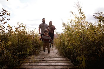Boy Running on Bridge Near His Parents