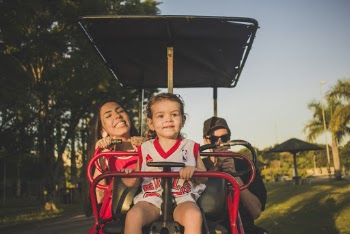 Boy Sits in Cart in Front of Woman Smiling