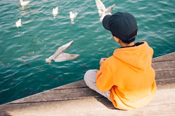 Boy Sitting Near Body of Water