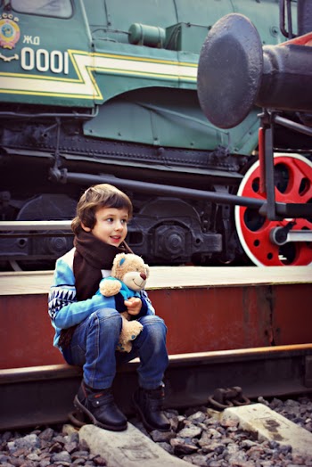 Boy Sitting Near Train While Holding Bear Plush Toy