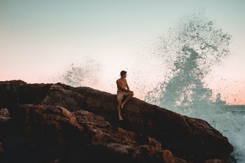 boy sitting with waves splashing