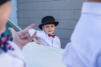 boy standing on side of white car