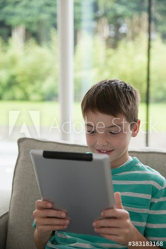 Boy using digital tablet on sofa