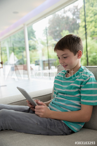Boy using digital tablet on sofa