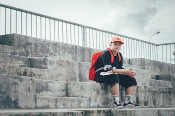 Boy Wearing Black Shirt Sitting On Concrete Staircase Holding Skateboard