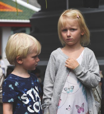 Boy Wearing Blue and White Stay Cool Print Crew-neck T-shirt Next to Girl Wearing White and Teal Butterfly Printed Scoop-neck Shirt and Gray Open Long-sleeved Cardigan