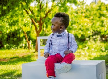 Boy Wearing Blue Shirt and Red Pants Sitting on Table