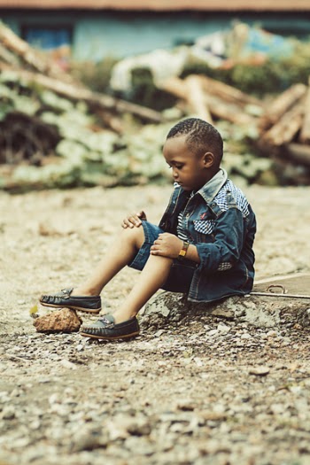 Boy Wearing Denim Jacket and Shorts With Pair of Shoes