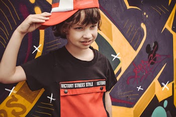 Boy Wearing Fitted Cap While Standing Beside Graffiti