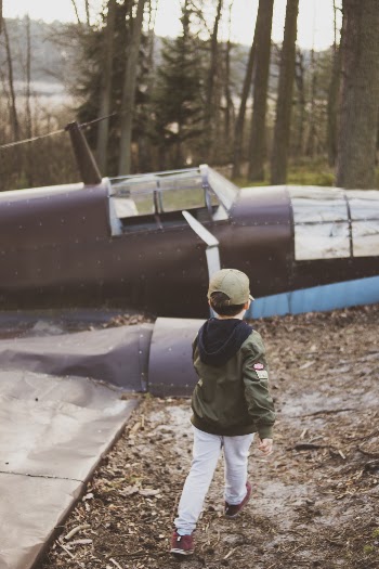 Boy Wearing Green Jacket Besides Brown Plane