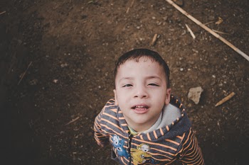 Boy Wearing Orange and Black Striped Teletubbies Print Zip-up Hoodie Jacket Standing on Brown Soil