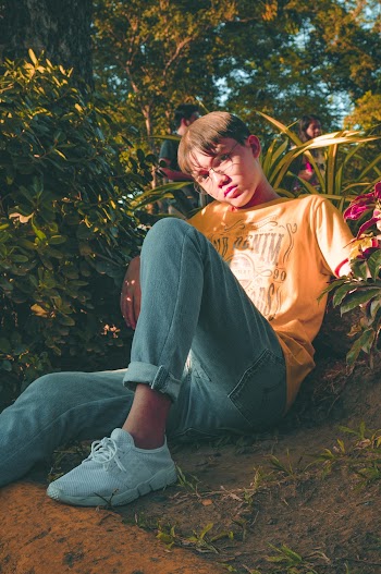 Boy Wearing Orange T-shirt and Blue Jeans Sitting on the Ground