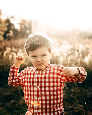Boy Wearing Red and White Checked Collared Button-up Long-sleeved Shirt Standing While Showing Angry Face