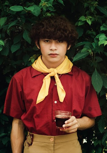 Boy Wearing Scout Uniform Holding Glass Standing Beside Green Plants