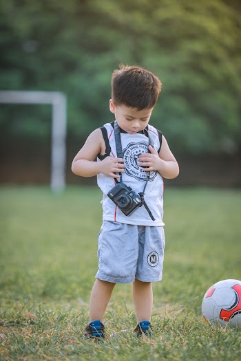 Boy Wearing White Shirt Carrying Black Camera