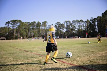 Boy Wearing Yellow and White Jersey Playing Soccer Field