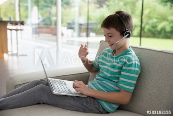 Boy with headset and laptop video chatting on sofa