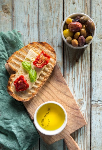 Bread With Toppings and Gray and Green Olives in Bowl