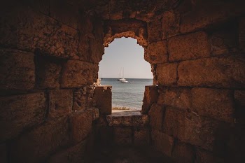 bricked hole showing white sail boat on water at daytime
