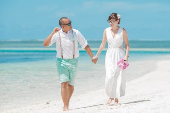 Bride and groom holding hands while walking on seashore