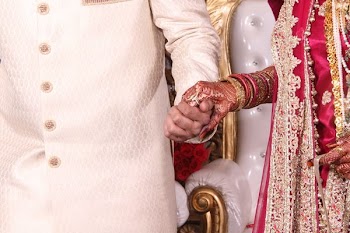 Bride in red and gold dress holds hands with groom in India