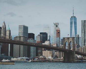Brooklyn bridge with body of water under gray sky during daytime