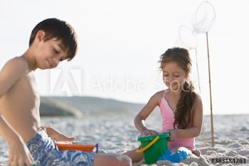 Brother and sister building sandcastle on sunny beach