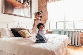Brother And Sister Playing On Bed
