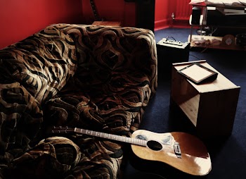 Brown Acoustic Guitar Leaning on Brown Velvet Couch