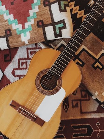 brown acoustic guitar on brown textile