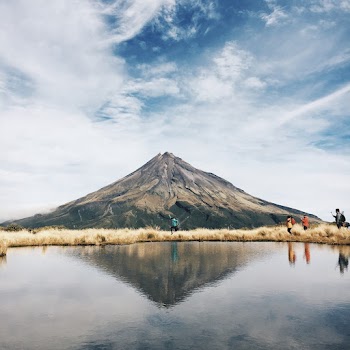 Brown and Black Mountain in Front of Body of Water