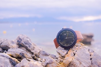 Brown and Black Round Analog Watch on Beige Rocks