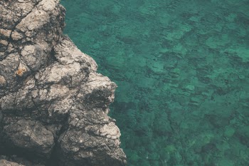 Brown and Gray Rock Formation Beside Calm Body of Water at Daytime
