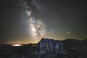 brown and gray wooden house under stars on sky during nighttime