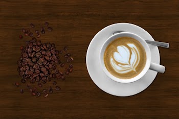 Brown and White Espresso in White Coffee Mug Beside Coffee Beans