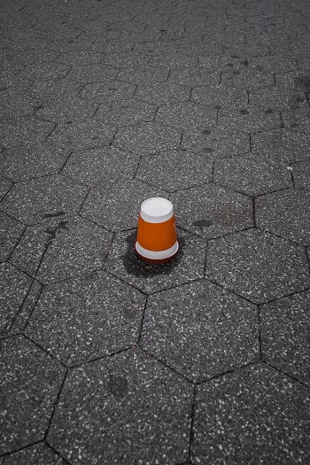 Brown and White Plastic Cup Upside Down on Gray Pavement