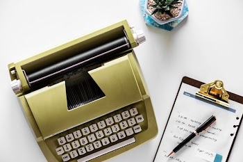 brown and white typewriter near black file board