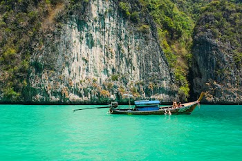 Brown Blue Boat Near Cliff and Water